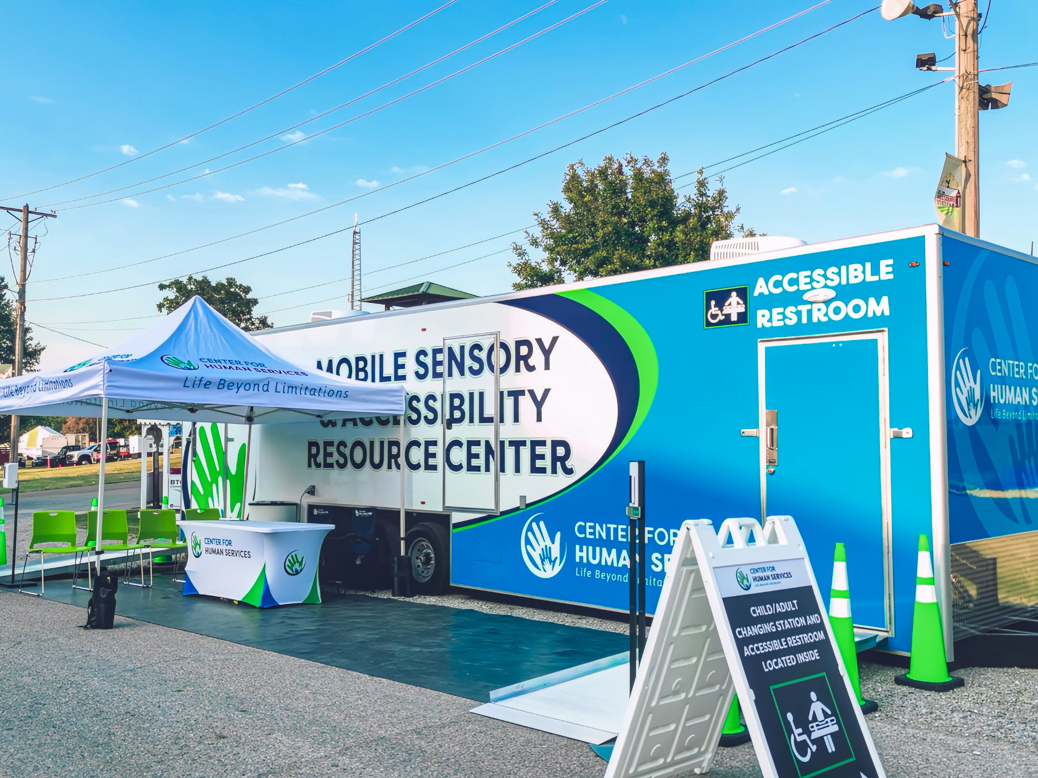 Outdoor Mobile Sensory Accessibility trailer with restroom, seating, and info table.
