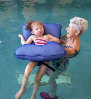 A young girl and her instructor swimming during a water therapy session