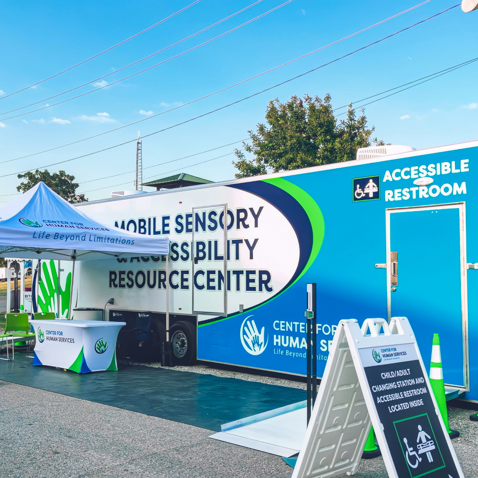 Outdoor Mobile Sensory Accessibility trailer with restroom, seating, and info table.