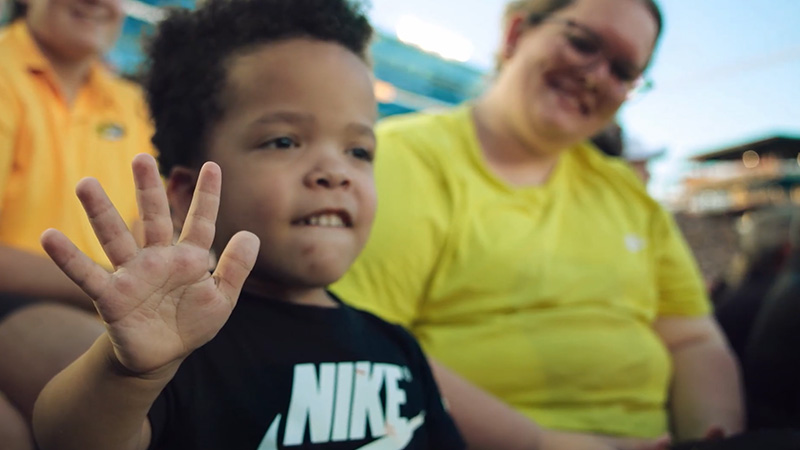 A young CHS client at a MU game waving to the crowd