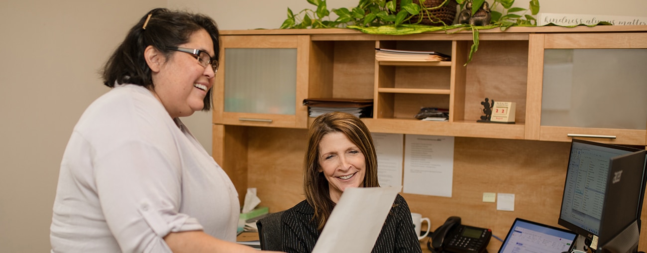 Women in an office looking at a document and smiling.