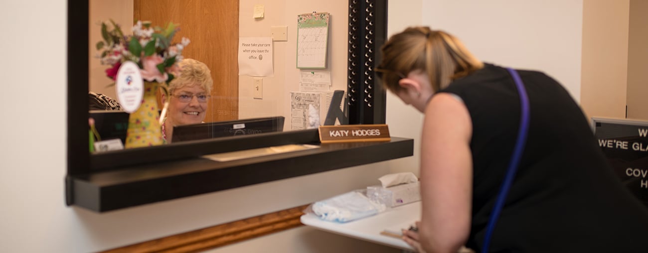 A women filling out an application for a new career at CHS in front of a reception desk