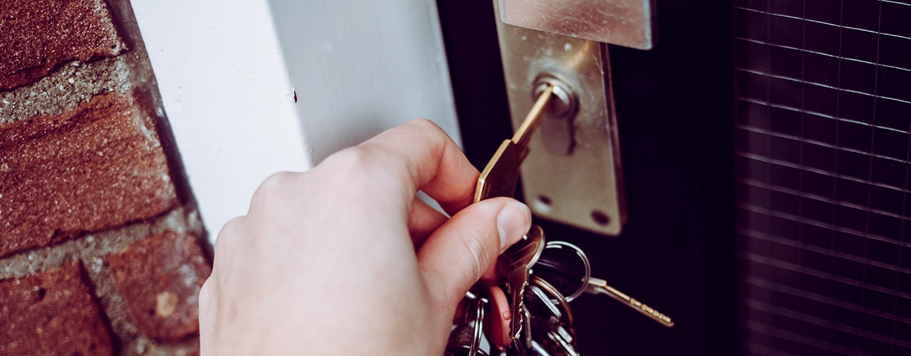 A hand opening a door with keys