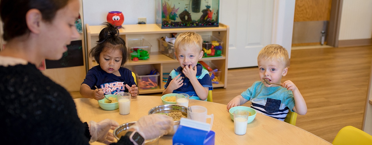 A group of preschool age kids eating breakfast at a Center for Human Services child development facility