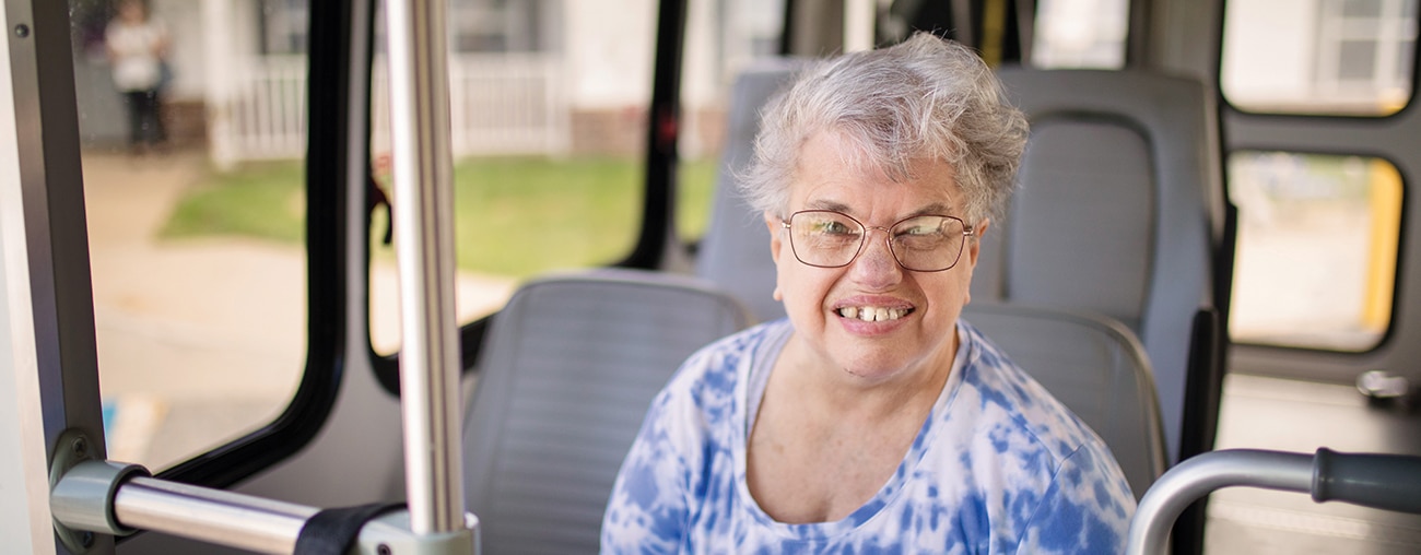 A senior lady on the bus smiling.