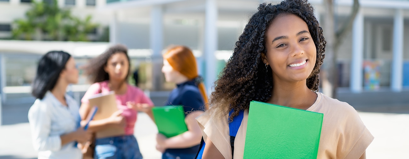 A high school student walking outside with books after school