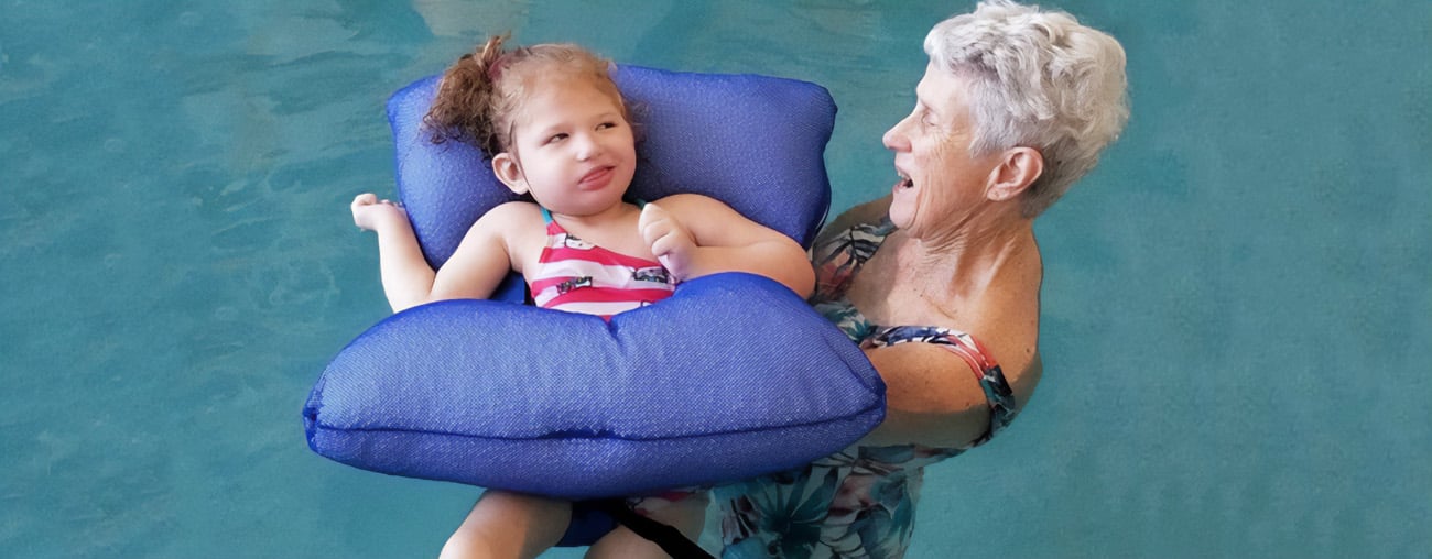 A young girl and her instructor swimming during a water therapy session