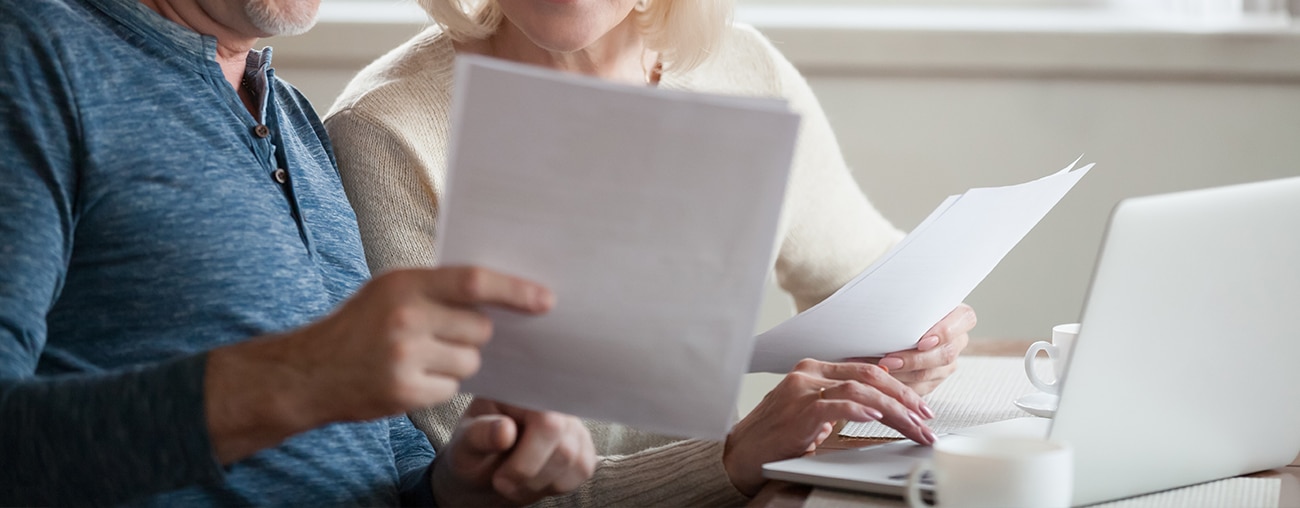 A man and a woman comparing documents in front of a computer.