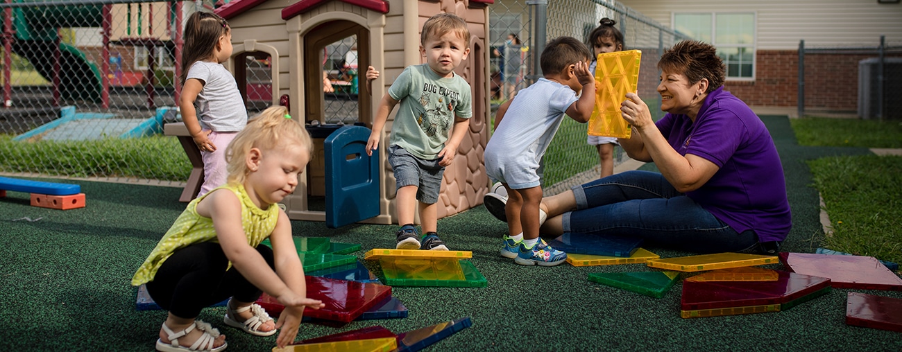 Children playing on a playground with a CHS caregiver